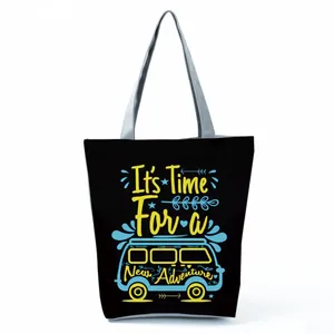 Close-up detail of the black canvas tote bag with 'New Adventure' camper van print.