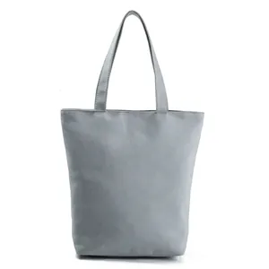 Close-up detail of a minimalist grey canvas tote bag featuring sturdy shoulder straps
