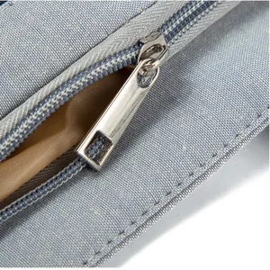 Close-up detail of silver metal zipper and blue canvas fabric on shoulder bag