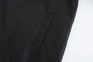 Detail shot of a black hooded jacket pocket with clean stitching and windproof fabric.