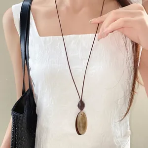 Vintage irregular oval resin pendant necklace with brown wax cord worn by woman