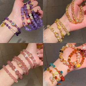 Primer plano de pulseras de cuentas de cuarzo fresa y amatista natural apiladas en varios colores.