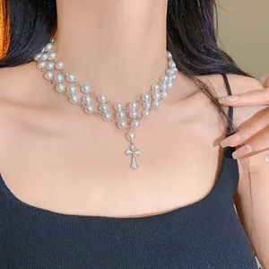 Close-up of elegant double-layer pearl necklace with a zircon cross pendant on model.