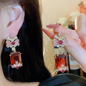 Macro view of elegant vintage earrings with red square stones and pink floral accents