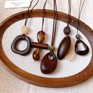 Set of five vintage-style resin necklaces with irregular shapes on a wooden tray