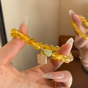 Primer plano de pulsera de cuentas amarillas con calabaza de jade y colgante rosa