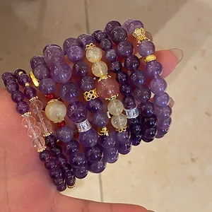 Detalle de pulseras de cuentas de amatista y cristal de fresa apiladas con adornos