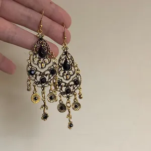 Detailed view of vintage gold teardrop earrings with black faceted crystals and tassels