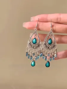 Close-up of vintage ethnic water drop earrings with teal crystals and bead tassels