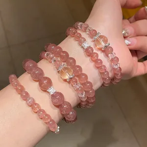 Primer plano de varias pulseras de cuentas de cuarzo fresa y cristal en capas finas.