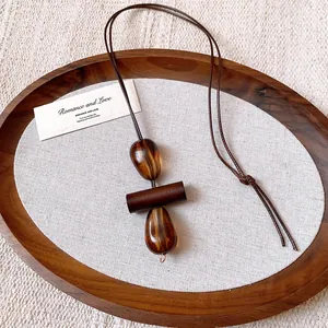 Close-up detail of retro wax cord necklace featuring irregular amber-textured oval resin pendants