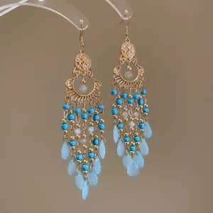 Bohemian tassel earrings with gold finish, turquoise beads, and light blue teardrops.