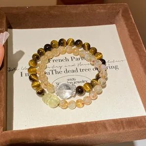 Primer plano de pulseras de cuentas de ojo de tigre y cuarzo rutilado en caja de regalo.