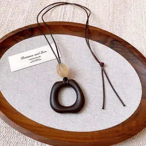 Close-up of irregular dark brown oval pendant necklace with minimalist wax cord