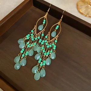 Detailed view of ethnic vintage tassel earrings with green beads and water-drop crystals