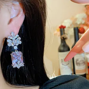 Detailed view of elegant purple square gemstone dangling earrings worn on ear, palace style.