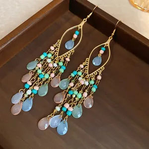 Detail of ethnic tassel earrings with multi-colored beads and teardrop crystal pendants.