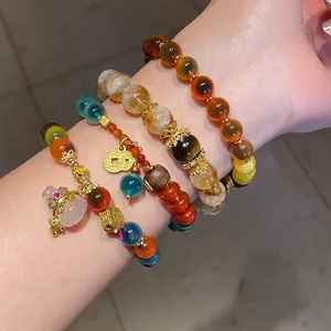 Primer plano de pulseras de piedras preciosas coloridas en capas con dijes de oro.