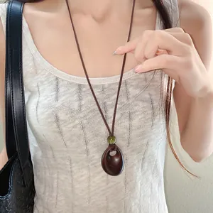 Detailed shot of a vintage-style brown wax cord necklace with an irregular oval pendant.