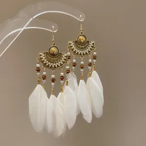 Detail showing elegant white feather tassels and tribal gold metal on bohemian earrings.