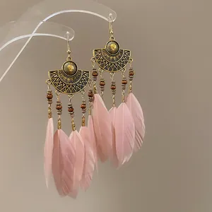 Close-up detail of vintage bohemian pink feather tassel earrings with ethnic metal plates