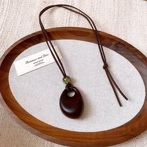 Close-up detail of vintage irregular oval wood-look pendant hanging on brown wax cord