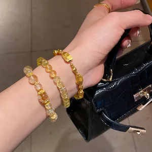 Primer plano detallado de tres pulseras apiladas de oro y cuentas de cristal amarillo en la muñeca