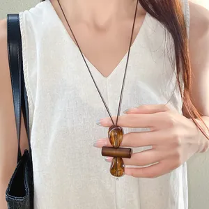 Minimalist irregular amber-toned pendant necklace with wooden detail on dark brown wax cord