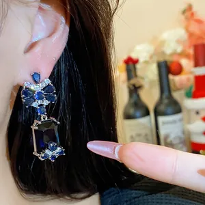 Close-up of elegant royal blue square zircon earrings with floral clusters on ear
