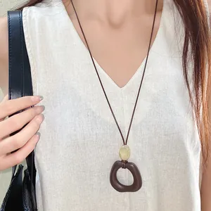 Close-up of a retro wax cord necklace with irregular brown pendant on linen top.