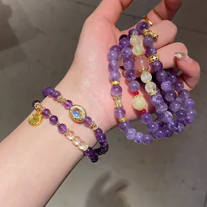 Detalle de pulseras de cuentas de amatista y cuarzo fresa en capas con dijes dorados.