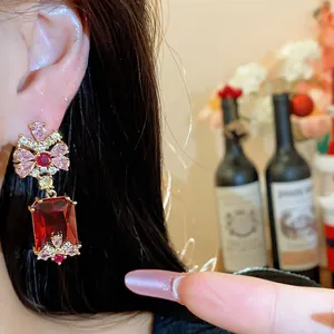 Close-up of elegant palace style red square zircon drop earrings with pink stones on ear