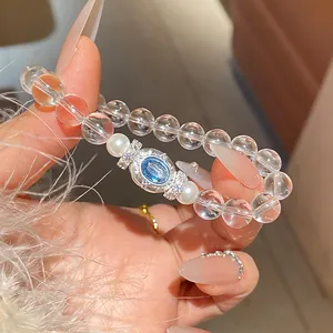 Primer plano de una elegante pulsera de cuentas transparentes con gema azul y perlas