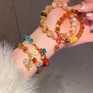 Primer plano de pulseras de cristal con cuarzo fresa y variados colgantes dorados.