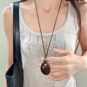 Detailed close-up of a rustic irregular oval wooden pendant necklace on a model.