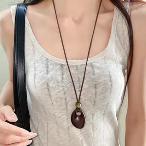 Close-up detail of vintage irregular oval wooden pendant necklace on a wax cord for women