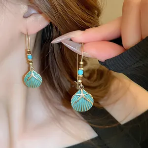 Detailed close-up of retro teal enamel shell hook earrings featuring starfish charms on a model