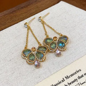 Close-up of vintage butterfly dangle earrings with iridescent green and pink glass drops