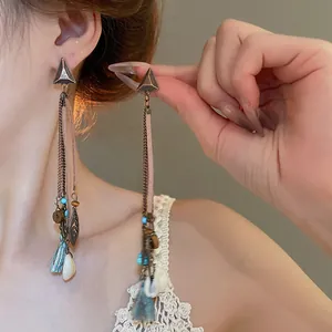 Close-up detail of vintage bohemian dangle earrings with leaf charm and blue beads