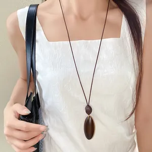 Asian model wearing a retro irregular oval wooden pendant necklace with wax cord