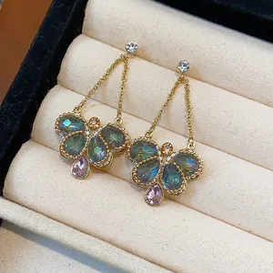 Detailed view of elegant butterfly earrings with teal and pink crystals in gold