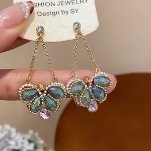 Detailed view of gold butterfly dangle earrings featuring colorful crystal glass stones.