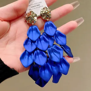 Close-up detail of stylish blue petal tassel earrings with textured golden metal studs
