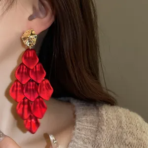 Close-up of elegant red petal tassel earrings with a unique hammered gold stud design