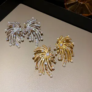Close-up of firework stud earrings with zircons and pearls in gold and silver