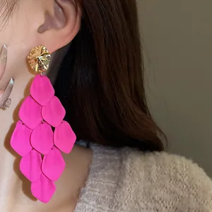 Close-up of vibrant magenta petal tassel earrings with a gold irregular stud detail