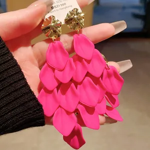Close-up detail of vibrant pink petal tassel earrings with gold-toned wave disc stud.