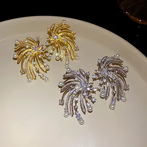 Close-up of zircon firework stud earrings with pearl accents in gold and silver