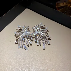 Detailed close-up showing firework design zircon stud earrings with elegant white pearl accents