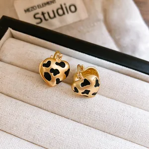 Close-up of gold heart-shaped earrings with black cow print in a jewelry box.